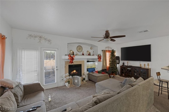 living room featuring carpet, ceiling fan, and a tiled fireplace