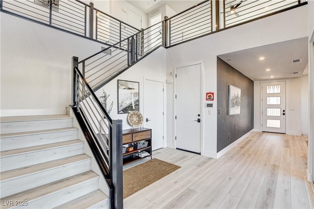 foyer entrance with a towering ceiling and light hardwood / wood-style flooring