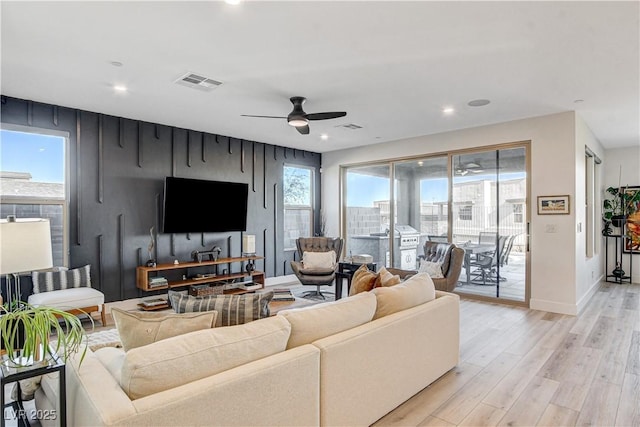 living room with light hardwood / wood-style flooring, ceiling fan, and a healthy amount of sunlight