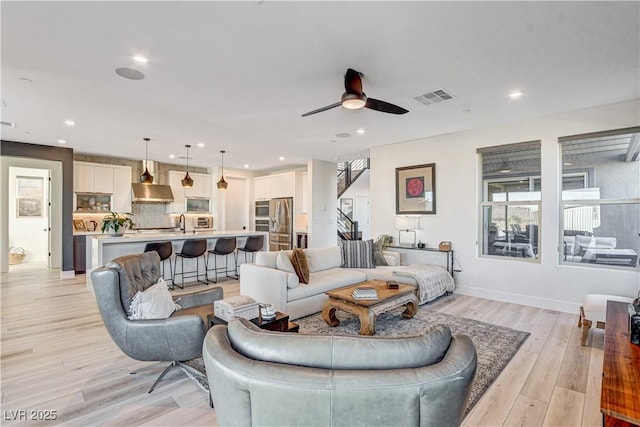 living room with ceiling fan, light hardwood / wood-style floors, and sink