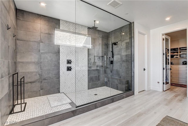 bathroom with tiled shower and hardwood / wood-style floors