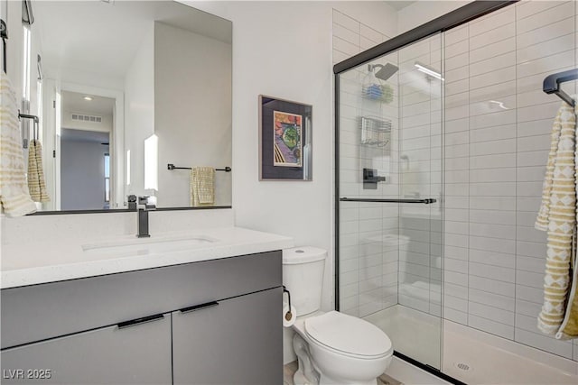 bathroom with an enclosed shower, vanity, and toilet