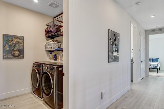 laundry area with washer and clothes dryer and light hardwood / wood-style flooring