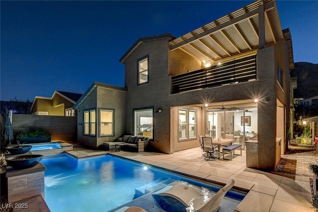 back house at night featuring a swimming pool with hot tub, a patio, an outdoor hangout area, and ceiling fan