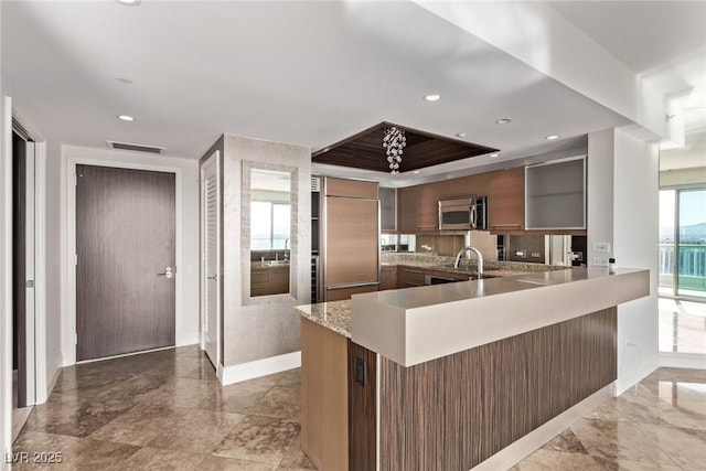 kitchen with paneled built in fridge, kitchen peninsula, and sink