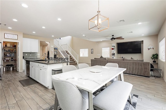 dining area with ceiling fan with notable chandelier and sink