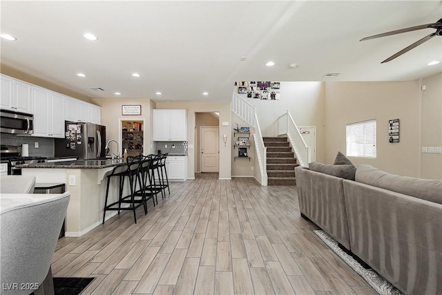 living room featuring ceiling fan, sink, and light hardwood / wood-style floors