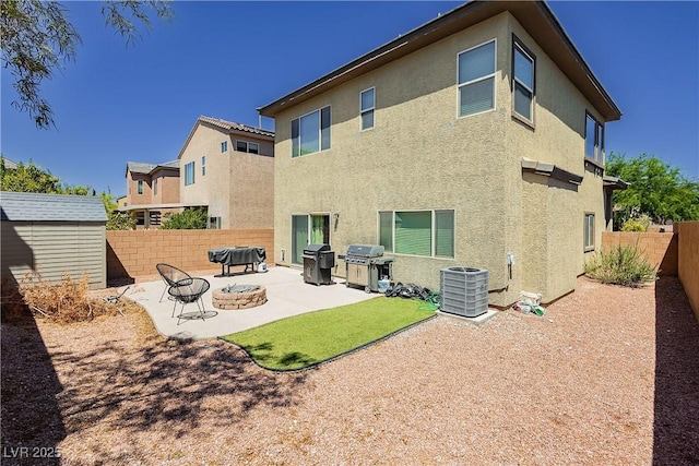 back of property featuring a fire pit, a storage unit, cooling unit, and a patio