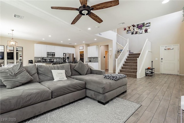 living room with ceiling fan with notable chandelier and sink