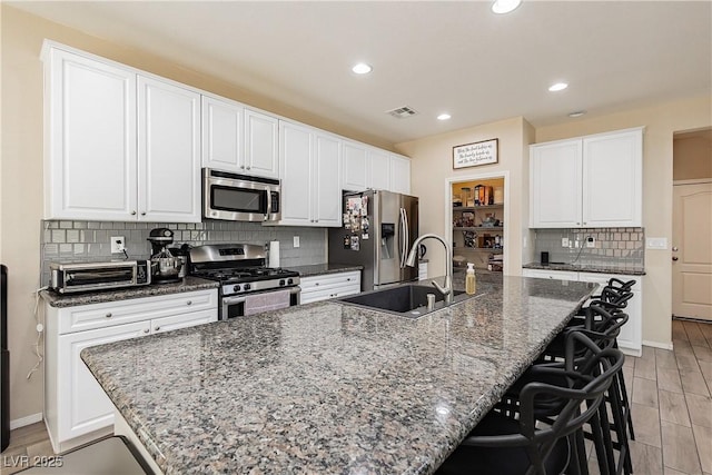 kitchen with sink, stainless steel appliances, a large island, and dark stone countertops