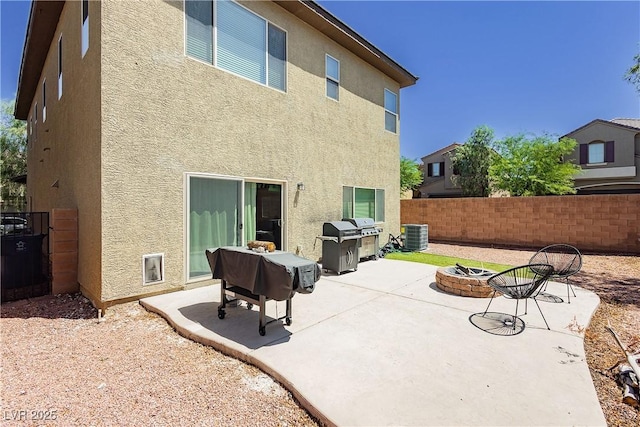 rear view of property featuring a patio, central AC unit, and an outdoor fire pit