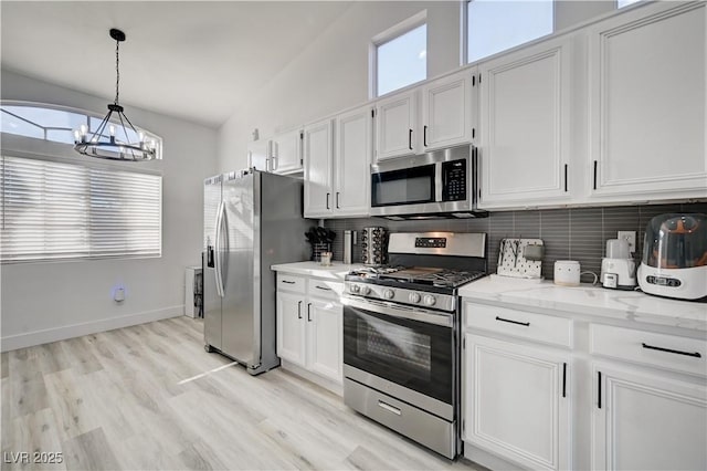 kitchen featuring vaulted ceiling, stainless steel appliances, white cabinetry, and backsplash