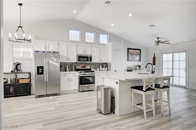 kitchen with white cabinets, a center island with sink, hanging light fixtures, and appliances with stainless steel finishes