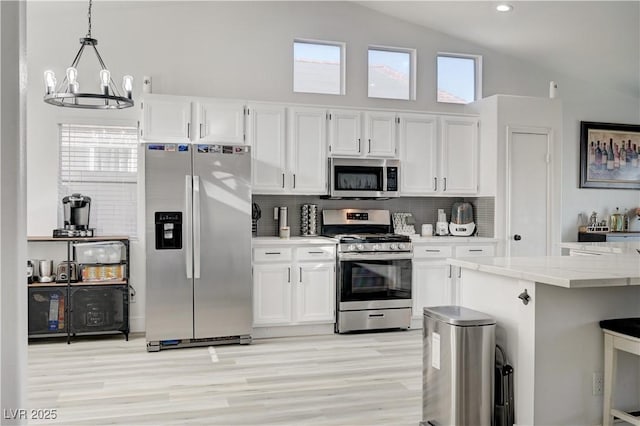 kitchen with tasteful backsplash, light stone counters, stainless steel appliances, pendant lighting, and white cabinetry