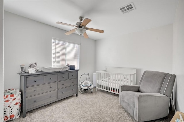 carpeted bedroom with ceiling fan and a nursery area