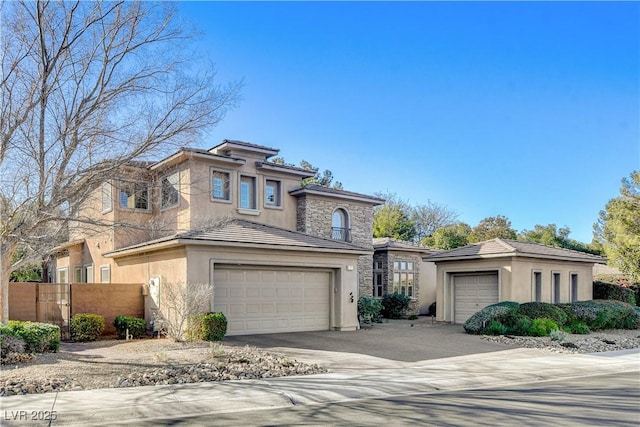 view of front facade featuring stucco siding, stone siding, fence, concrete driveway, and a tiled roof