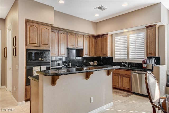 kitchen with a kitchen bar, light tile patterned floors, black appliances, and a kitchen island