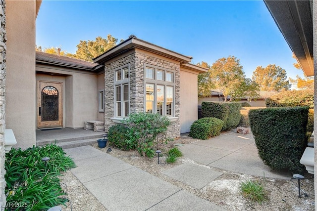 property entrance featuring stone siding and stucco siding