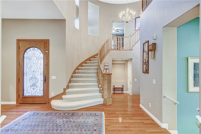 entrance foyer with hardwood / wood-style flooring, a towering ceiling, and a chandelier