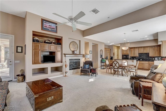 living room featuring light carpet, built in shelves, and ceiling fan