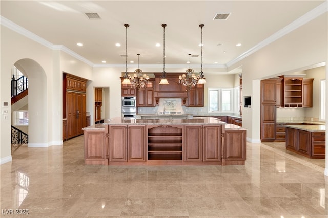 kitchen featuring hanging light fixtures, light stone counters, ornamental molding, and a large island