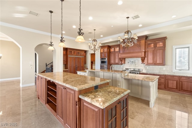 kitchen with light stone countertops, a spacious island, hanging light fixtures, backsplash, and a chandelier