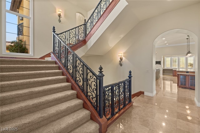 stairs with crown molding and a towering ceiling