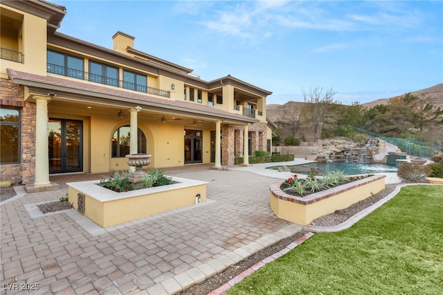 rear view of house featuring a balcony, french doors, ceiling fan, and a patio