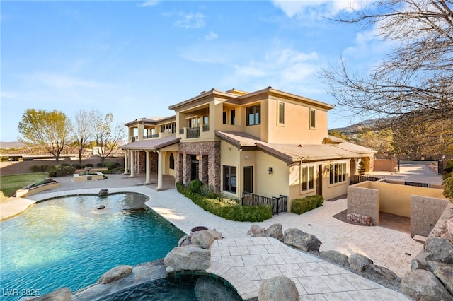 back of house featuring a patio area, a swimming pool with hot tub, and a balcony