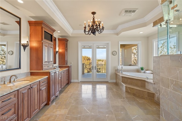 bathroom featuring crown molding, an inviting chandelier, a tray ceiling, french doors, and a relaxing tiled tub