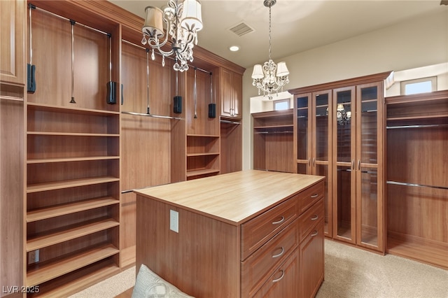 walk in closet with light colored carpet and an inviting chandelier