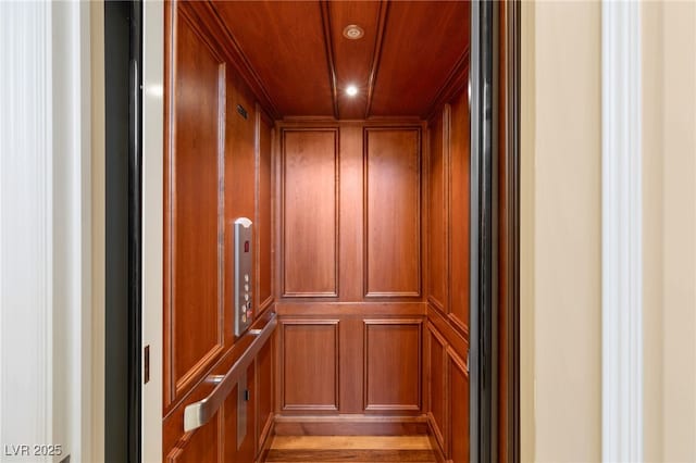 room details featuring elevator, wood walls, and wooden ceiling