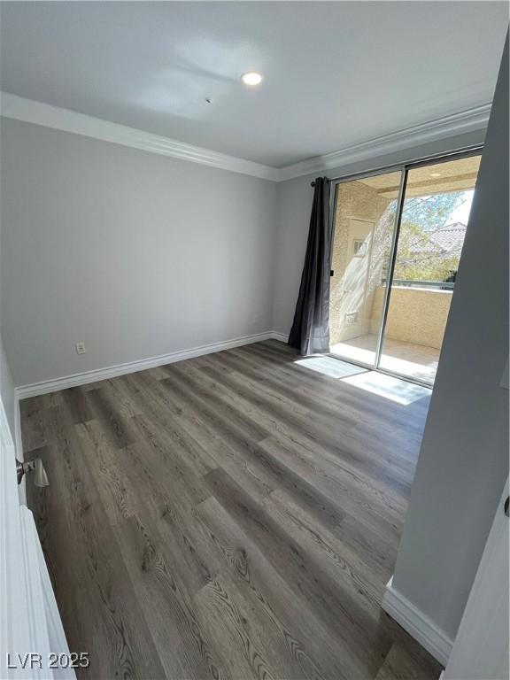 empty room featuring baseboards, ornamental molding, and wood finished floors