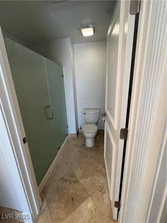 bathroom with a stall shower, baseboards, toilet, and tile patterned floors