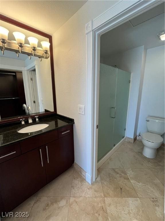 bathroom featuring a stall shower, baseboards, vanity, and toilet