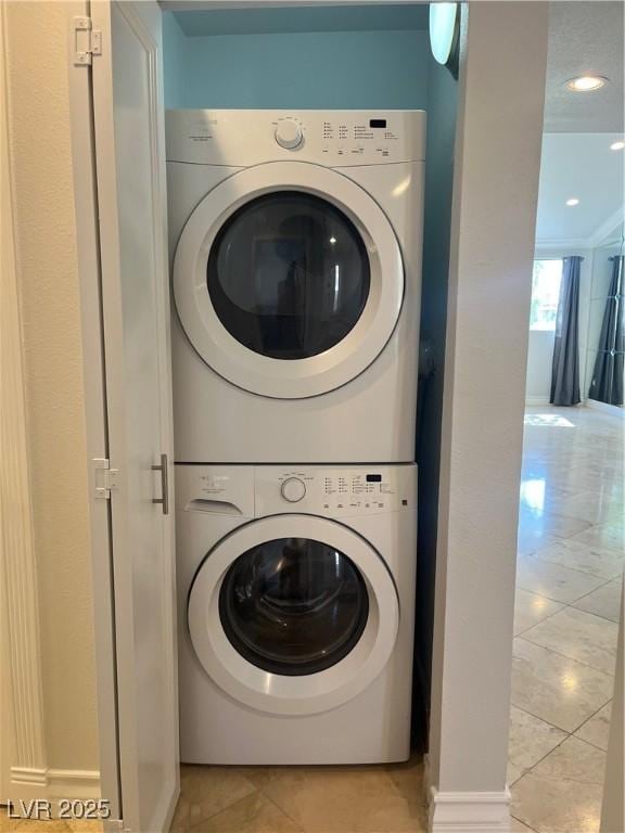 clothes washing area featuring light tile patterned floors, laundry area, and stacked washer / dryer