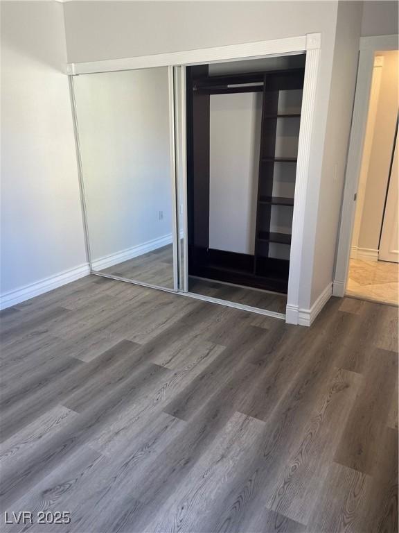 unfurnished bedroom with a closet, baseboards, and wood finished floors