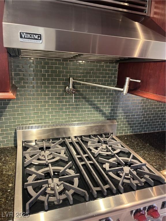 room details with tasteful backsplash, range with gas stovetop, dark stone countertops, and exhaust hood