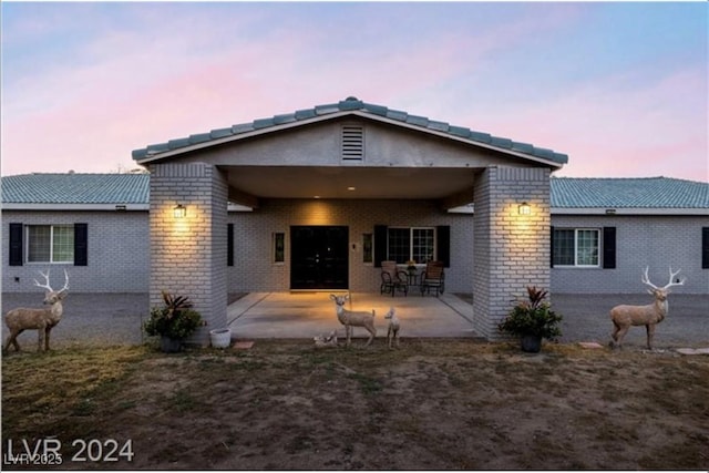 back house at dusk featuring a patio area