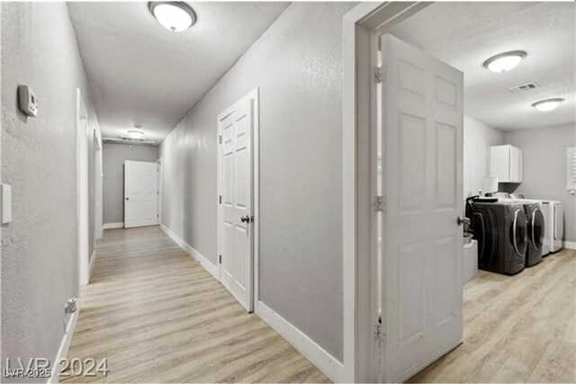 hallway with light wood-type flooring and separate washer and dryer