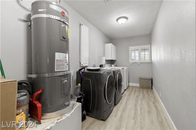 clothes washing area with cabinets, separate washer and dryer, light wood-type flooring, and water heater