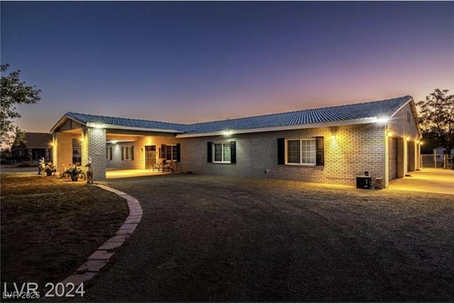 back house at dusk with central air condition unit and a garage