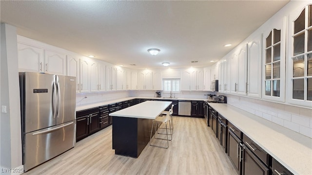 kitchen featuring white cabinets, appliances with stainless steel finishes, a center island, and a breakfast bar area