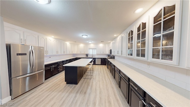 kitchen featuring a breakfast bar, stainless steel appliances, a kitchen island, and white cabinetry