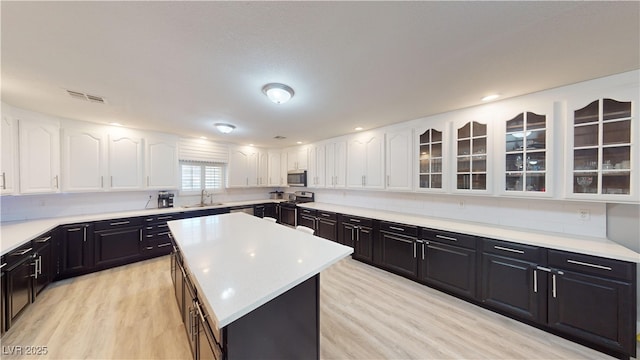 kitchen featuring a center island, white cabinetry, stainless steel appliances, and light hardwood / wood-style flooring