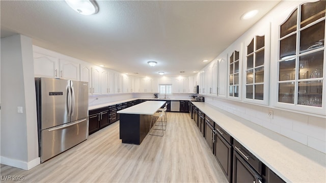 kitchen featuring white cabinets, a kitchen island, a kitchen bar, and appliances with stainless steel finishes