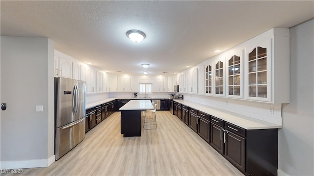 kitchen featuring appliances with stainless steel finishes, backsplash, a breakfast bar, a center island, and white cabinetry