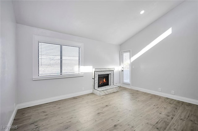 1701 E Katie Ave Unit 10, Las Vegas, NV 89119 - unfurnished living room featuring light wood-type flooring, vaulted ceiling, plenty of natural light, and a premium fireplace
