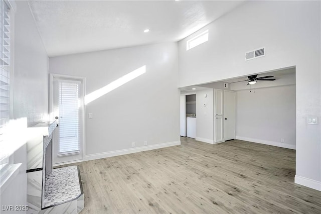 1701 E Katie Ave Unit 10, Las Vegas, NV 89119 - unfurnished living room featuring ceiling fan, light hardwood / wood-style flooring, a towering ceiling, and a healthy amount of sunlight