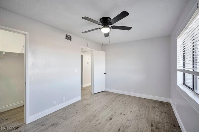 1701 E Katie Ave Unit 10, Las Vegas, NV 89119 - unfurnished bedroom with ceiling fan, light wood-type flooring, a spacious closet, multiple windows, and a closet